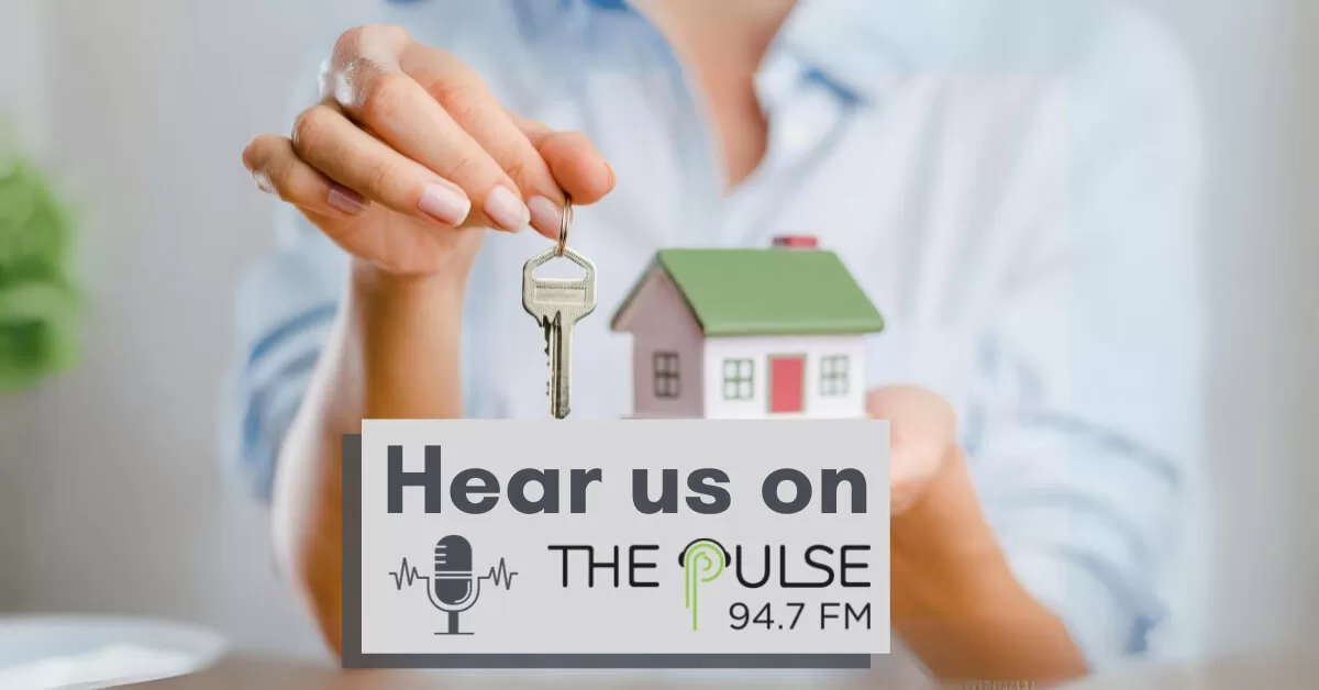 A woman holds a small model house in one hand and a house key in the other. The words say 'Hear us on The Pulse 94.7 FM'.
